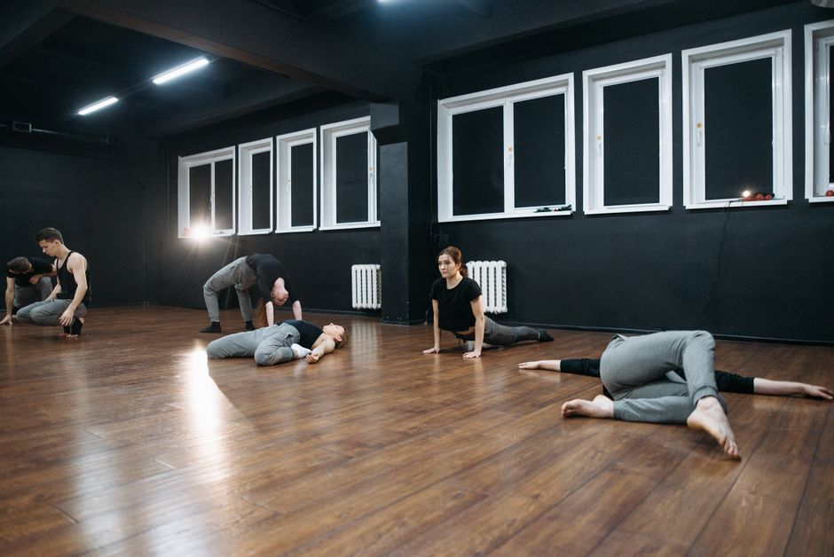Warm sunlit yoga studio with wooden floors, natural light, and studio props arranged in a calm, minimal space