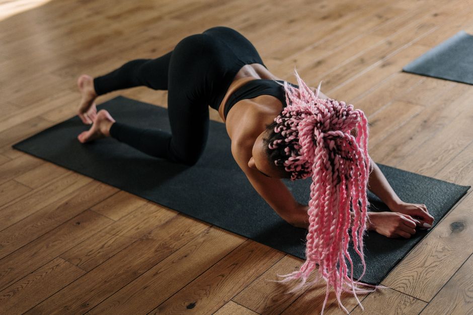 A teacher guiding a vinyasa flow class on a wood floor